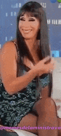 a woman is sitting on a couch and smiling while holding her hair .