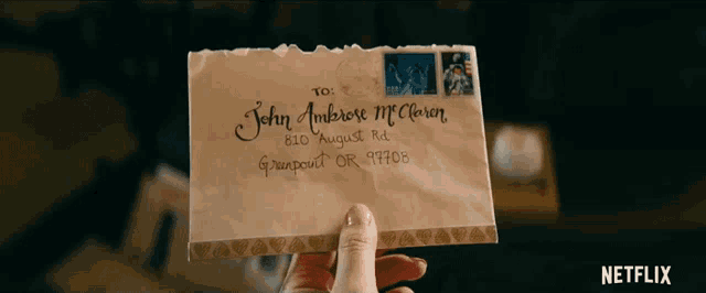 a person is holding an envelope addressed to john