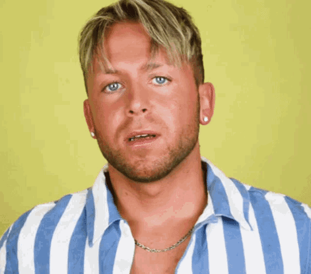 a man wearing a blue and white striped shirt with a necklace around his neck