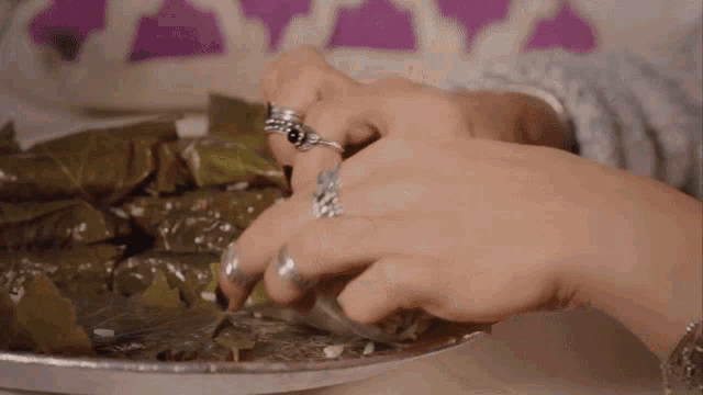 a close up of a person 's hands with rings on their fingers