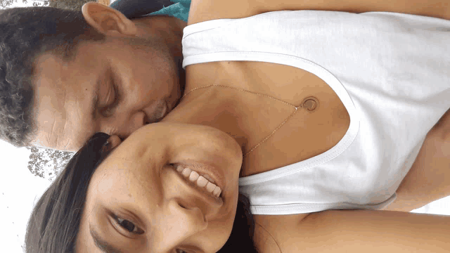 a man kisses the neck of a woman who is wearing a necklace