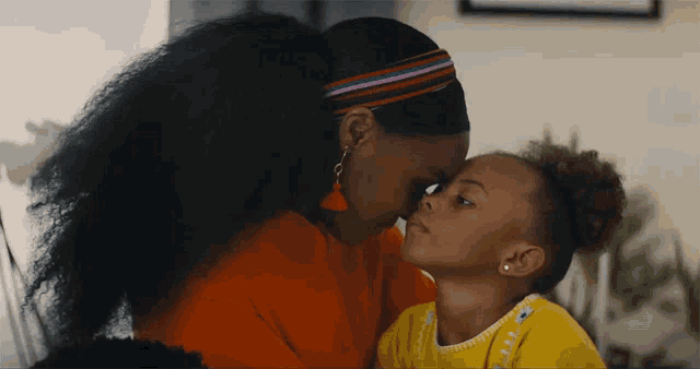 a woman and a little girl are touching foreheads