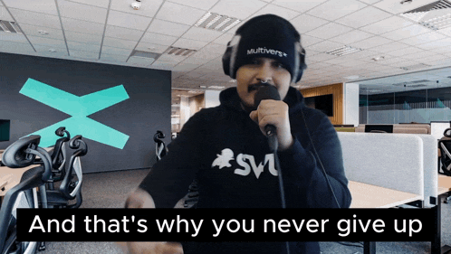 a man singing into a microphone with the words " and that 's why you never give up " behind him