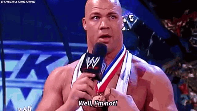 a man wearing a medal around his neck is talking into a microphone and saying well , i 'm not .