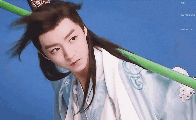 a young man with long hair is holding a green pole