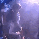 a group of people are dancing in a dark room at a party .