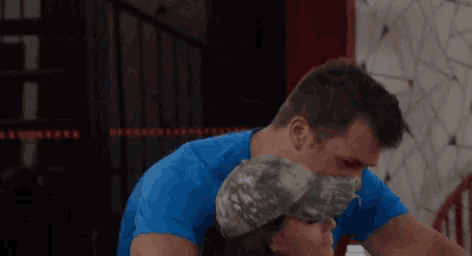 a man in a blue shirt is holding another man in a hat .
