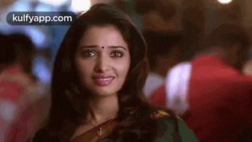 a close up of a woman wearing a green saree smiling .