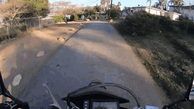 a person riding a motorcycle down a dirt road with a speedometer that reads 24