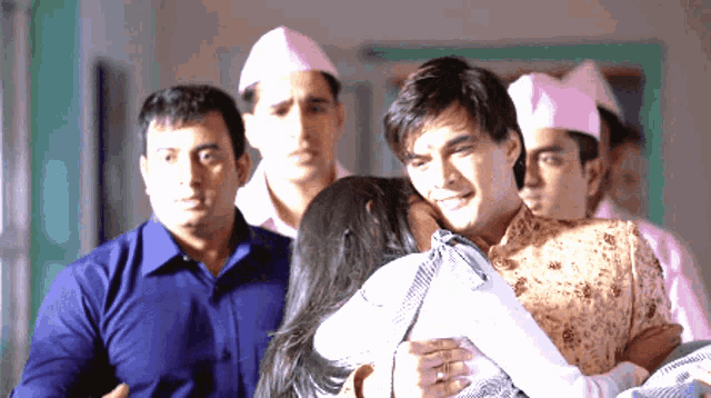a man is carrying a woman in his arms while other men look on