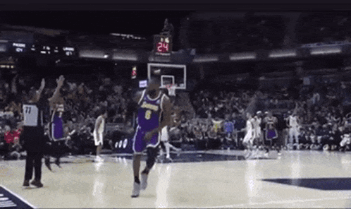 a basketball player in a purple jersey with the number 6 on it is jumping in the air during a game .