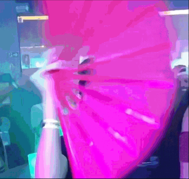 a woman holding a bright pink fan in front of her face