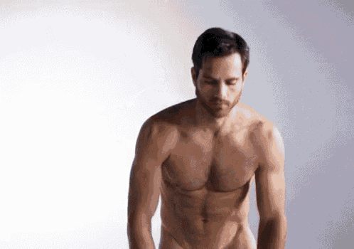 a shirtless man is standing in front of a white wall .