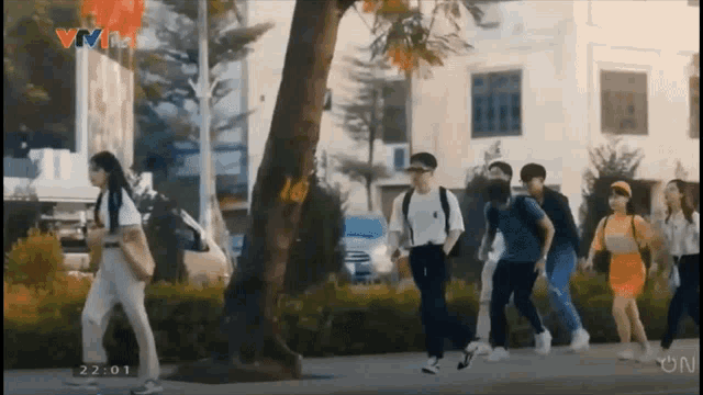 a group of people walking down a street with the time 22:01 on the screen