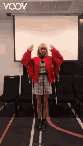 a woman in a red jacket stands in front of a projector screen with the word vcov on it