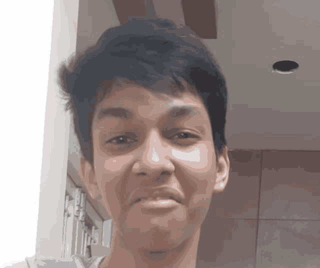 a young man is making a funny face in front of a wall