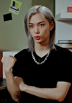 a young man with gray hair is wearing a black shirt and a silver necklace