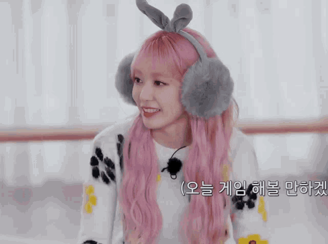 a girl with pink hair wearing ear muffs and a headband with a bunny ear