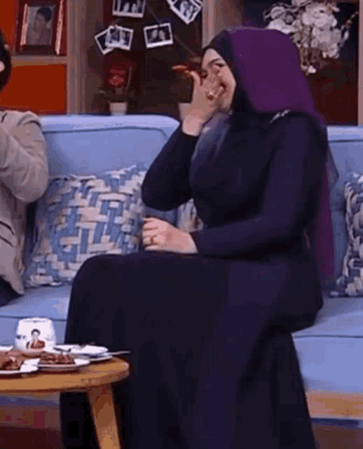 a woman in a hijab is sitting on a couch
