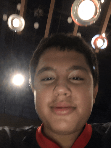 a young boy smiles in front of a ceiling with lights