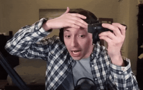 a man wearing headphones and a plaid shirt is holding a camera