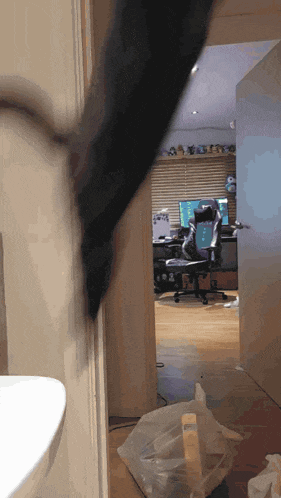 a person is standing in a room with a computer and a chair