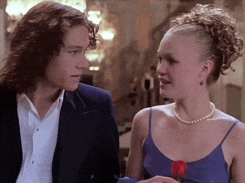 a man in a suit and a woman in a pearl necklace are looking at each other