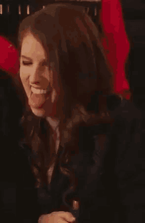 a woman is making a funny face with her tongue out while holding a bottle .