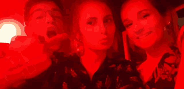 a man and two women are posing for a photo in a red light