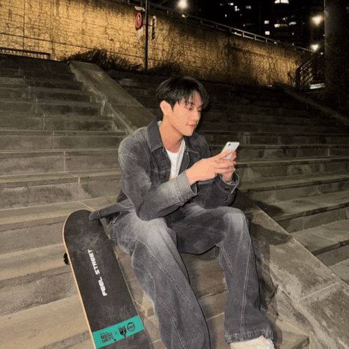 a man sits on a set of stairs with a skateboard that says feel street on it