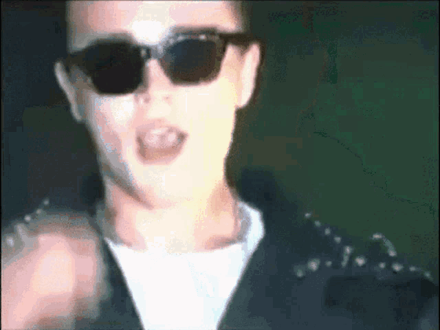 a man wearing sunglasses and a black jacket with studs on it