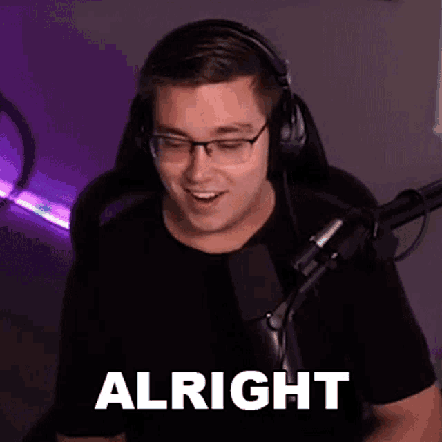 a man wearing headphones and glasses is sitting in front of a microphone and making a funny face .