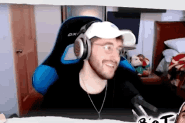 a man is wearing headphones and a hat while sitting in a chair .