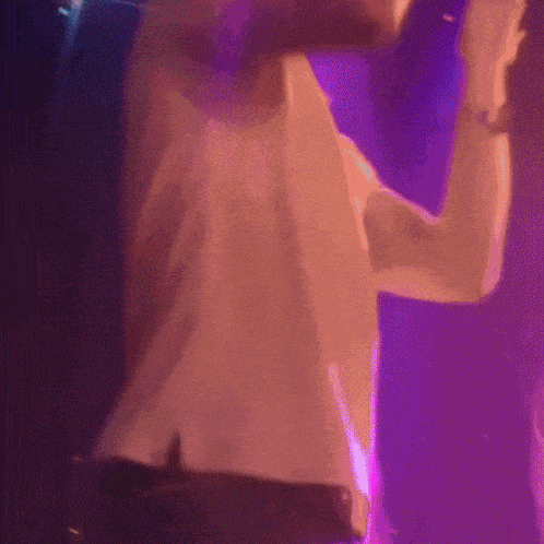 a man in a white shirt is dancing in a club