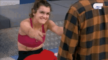 a woman in a pink top is sitting on a couch with a man in a plaid shirt
