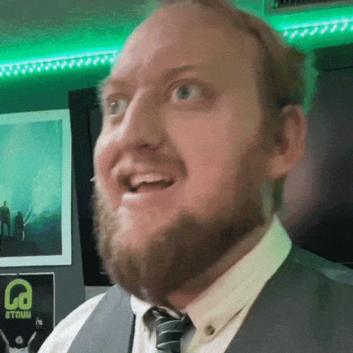 a man with a beard is smiling in front of a poster that says la on it