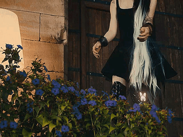 a woman in a black dress is standing in front of a wooden door