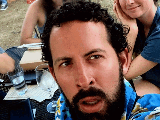 a man with a beard is sitting at a table with two other people