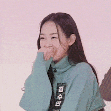 a woman wearing a blue sweater with chinese writing on it is laughing .