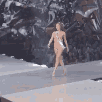 a woman in a bikini is walking down the runway at a beauty pageant .