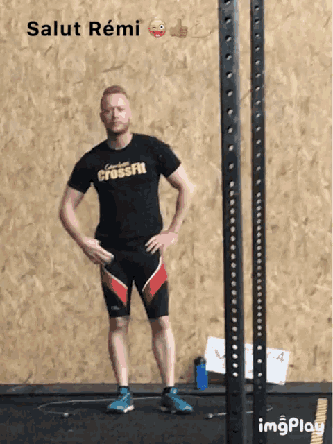 a man wearing a crossfit shirt stands in front of a gym rack