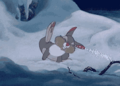 a cartoon rabbit is laying in the snow with a red hat on .