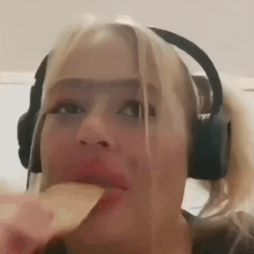 a woman wearing headphones is eating a piece of food .