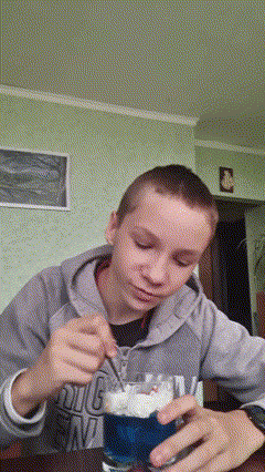 a boy wearing a hoodie that says big ena is stirring a blue drink with a spoon