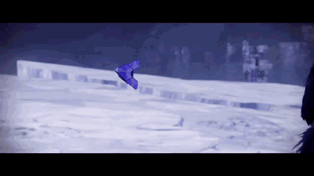 a blue kite is flying over a snow covered field