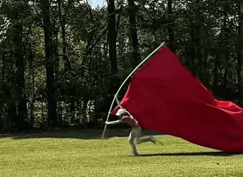 a person is running with a large red flag on a pole .