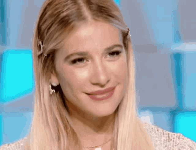 a close up of a blonde woman 's face with a blue background