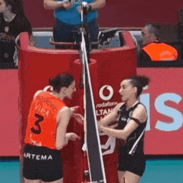two volleyball players are talking to each other on the court