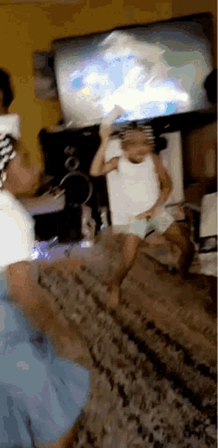 a little girl is jumping in the air in front of a tv