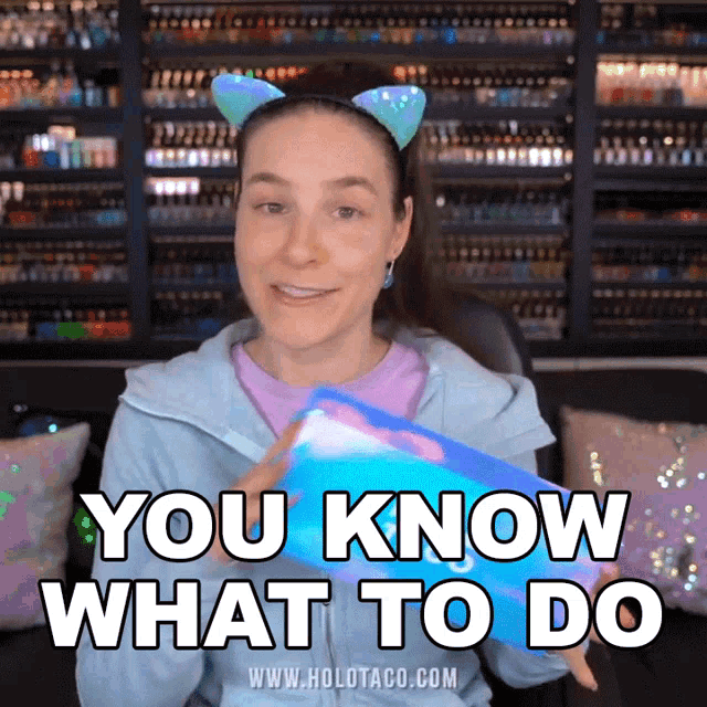 a woman wearing cat ears and a headband says " you know what to do "